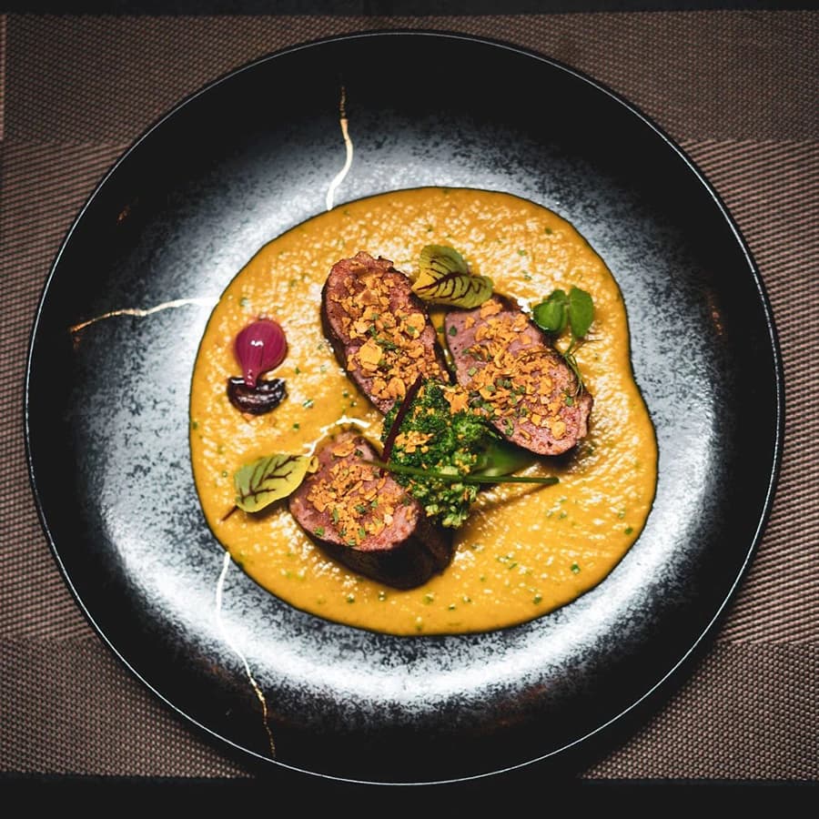 Seared fillets on a turmeric-coloured sauce in a wide black bowl