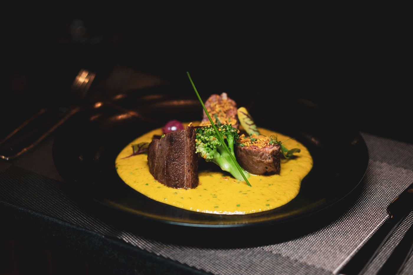 Spiced lamb on a saffron-yellow sauce with charred greens