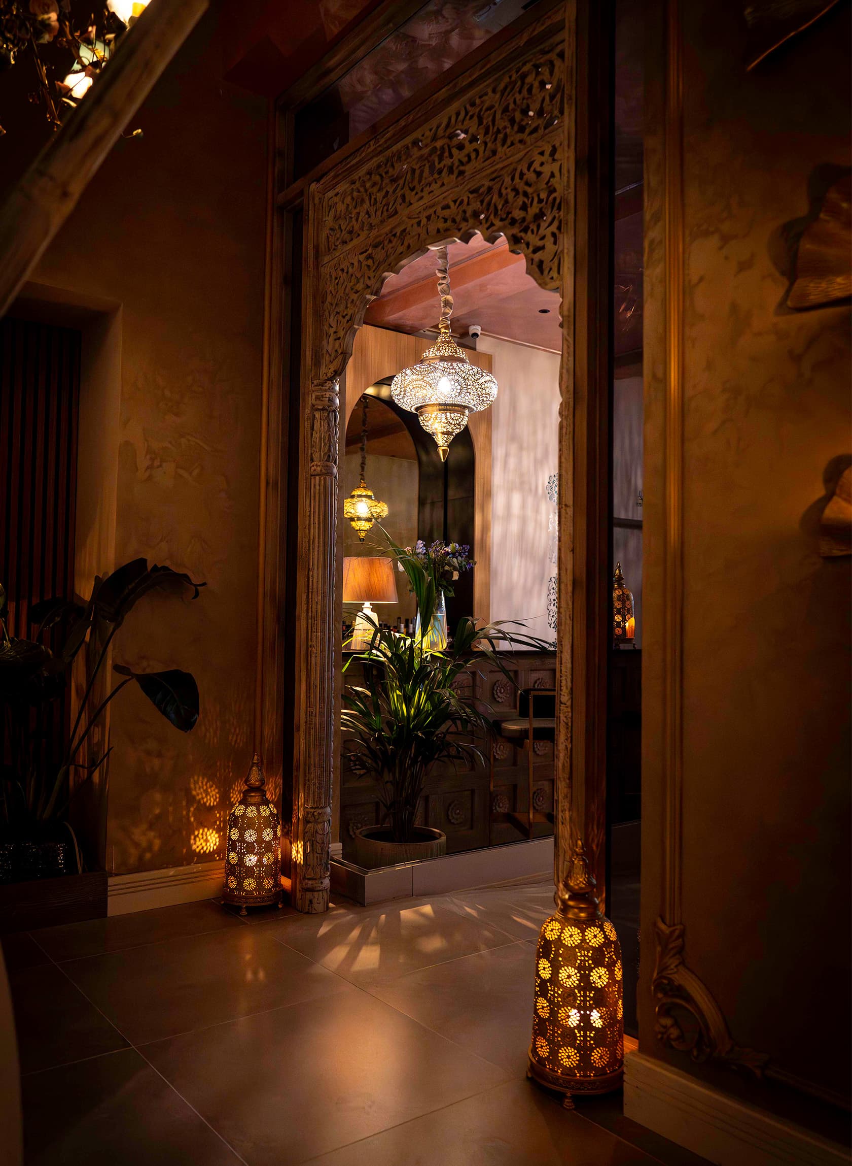 A lantern-lit passage through carved doorways into the dining room