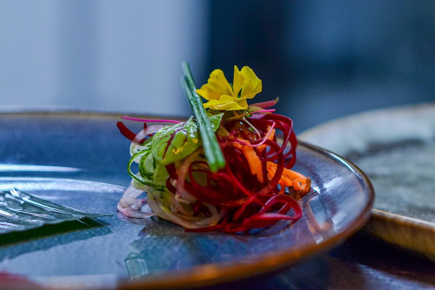 A dressed salad starter on a turquoise glazed plate