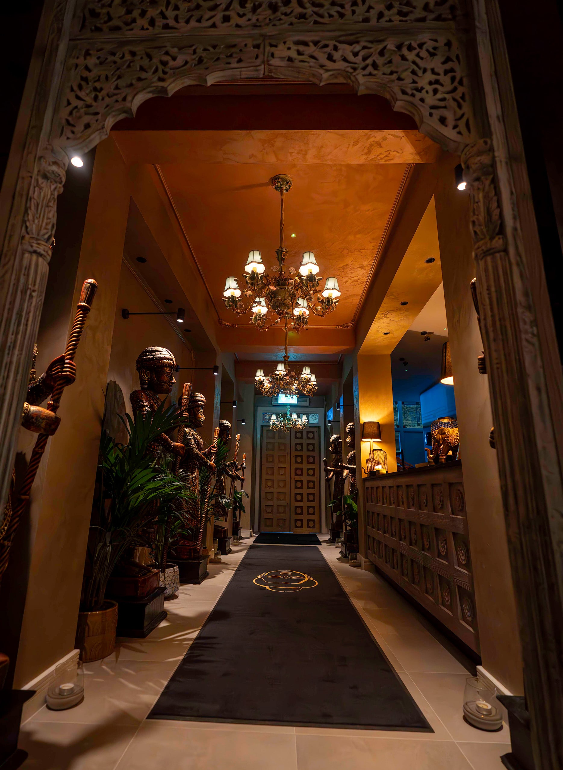 The entrance corridor at Leicester, carved archway lit by a chandelier