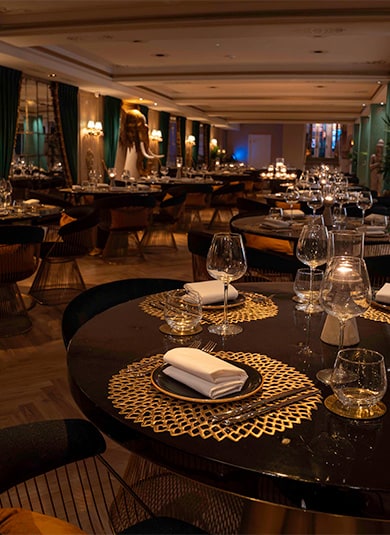 A laid table with glassware, linen and a woven gold placemat